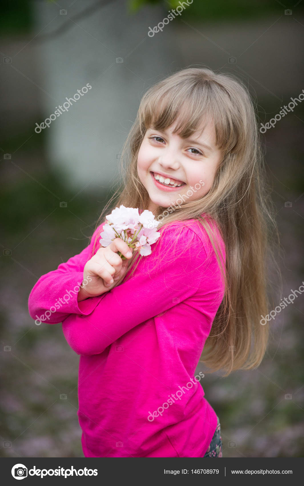 Small baby girl with smiling face holding pink sakura blossom ...