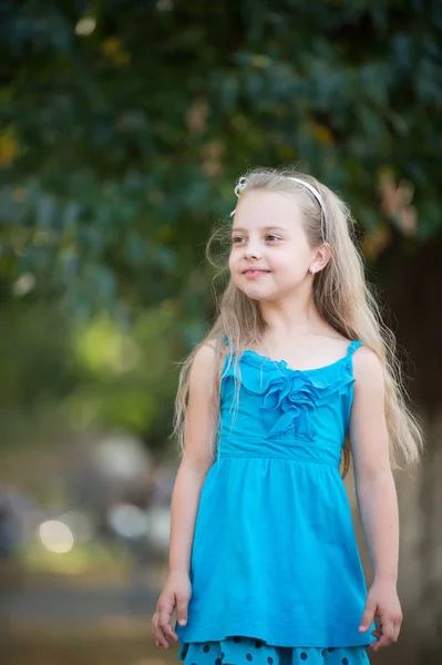 Liten flicka med leende ansikte i blå klänning utomhus — Stockfoto