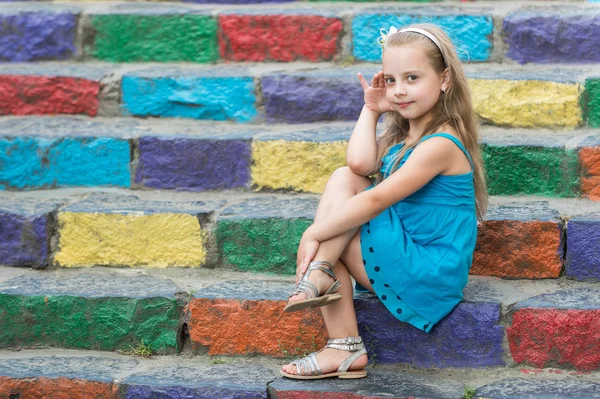 Small smiling baby girl in blue dress on colorful stairs — Stock Photo, Image