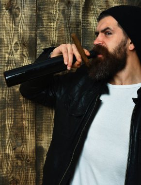 Sakallı, Kafkas hippisi elinde şişe, puro içiyor.