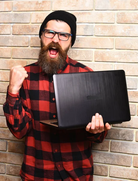 Bearded brutal caucasian hipster holding laptop — Stock Photo, Image