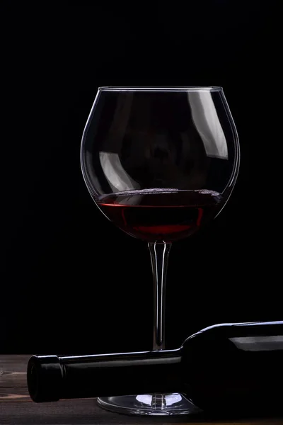 Vinho e garrafa com vinho sobre fundo preto — Fotografia de Stock