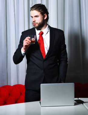 Sakallı adam, bir bardak viski, cep telefonu, dizüstü bilgisayarı olan iş adamı.