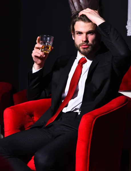 髭を生やしたビジネスマンが赤い椅子にウィスキーを持っていて — ストック写真