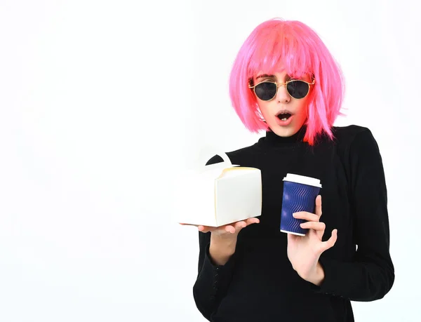 Niña en peluca rosa sosteniendo taza de café y caja de comida — Foto de Stock