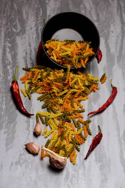 Torkade fusilli pasta, kyliga peppar, vitlök i skål plattan — Stockfoto