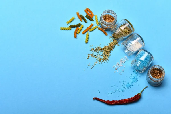 Salt, spices and herbs spilled from jars and dried fusilli
