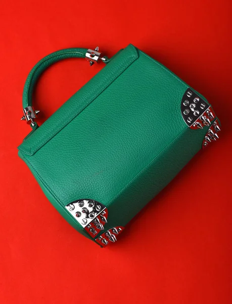 small womans leather green bag with metallic spikes on red