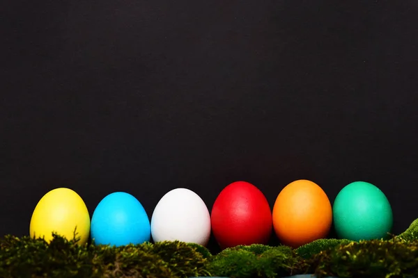 Huevos coloridos de Pascua pintados con musgo verde sobre fondo negro — Foto de Stock