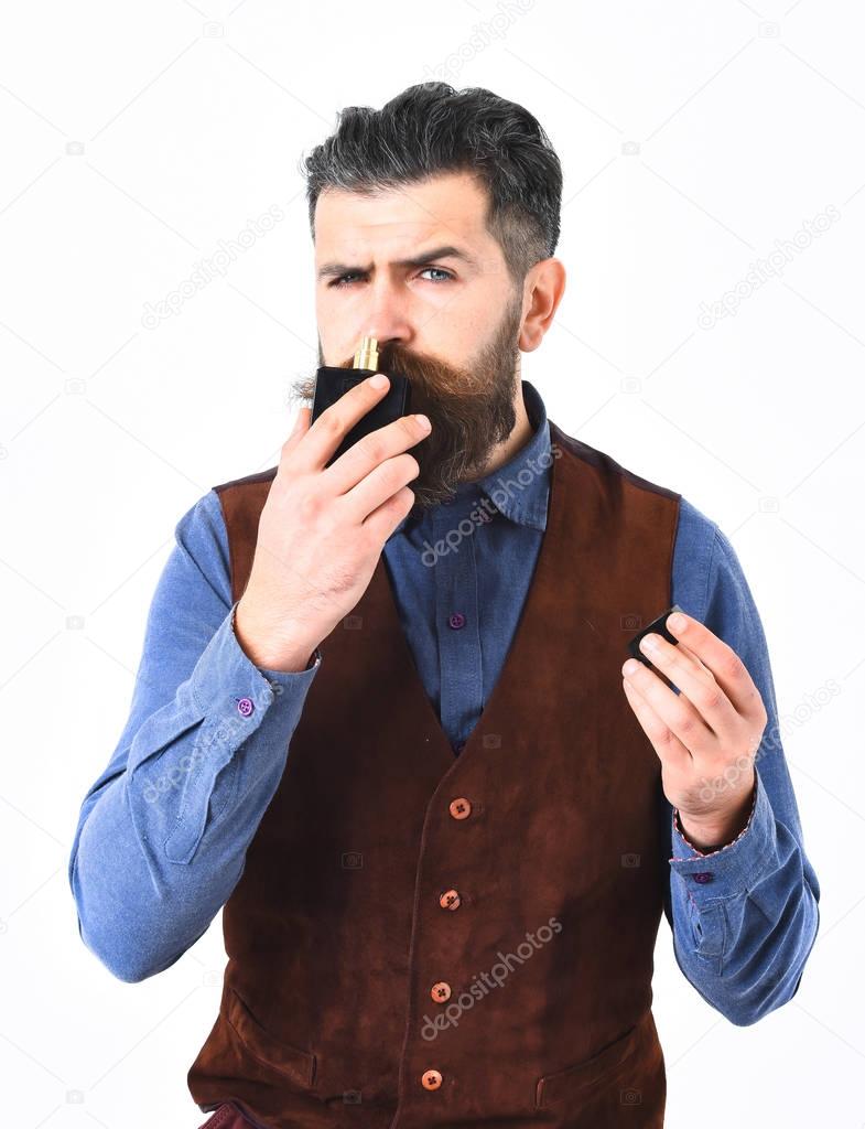bearded man sniffing perfume with serious face