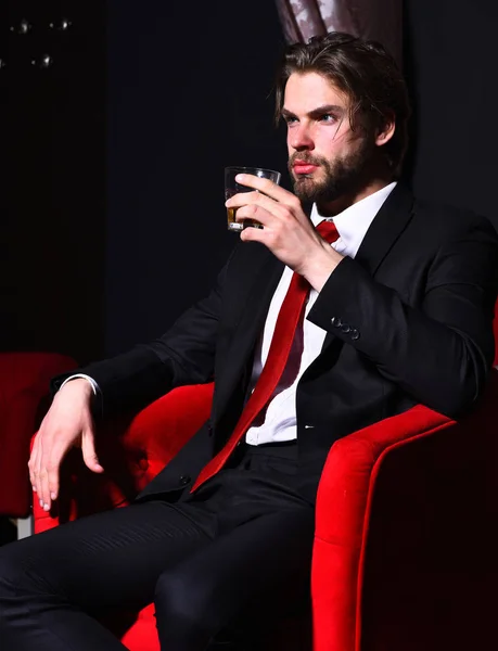 髭を生やしたビジネスマンが赤い椅子にウィスキーを持っていて — ストック写真