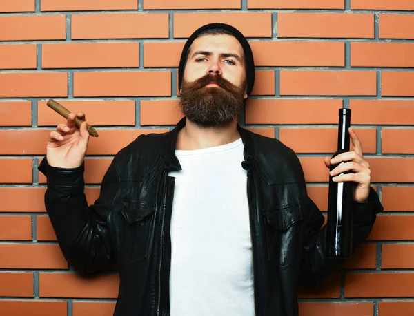 Barbudo brutal caucasiano hipster segurando garrafa e fumar charuto — Fotografia de Stock