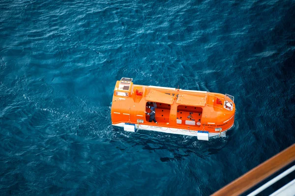 Orange rescue, livbåt för nödutrymning med människor på vatten — Stockfoto