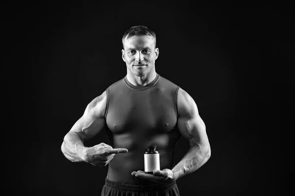 Hombre hermoso culturista con cuerpo muscular sostiene frasco de la píldora, esteroides —  Fotos de Stock