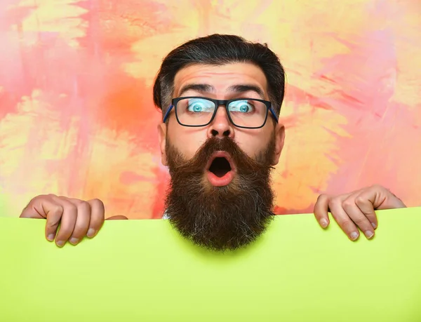 Hombre barbudo con cara sorprendida en gafas sobre fondo colorido — Foto de Stock