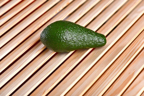 Frische grüne Avocado auf braunem Holztisch, glitzerndem Hintergrund — Stockfoto