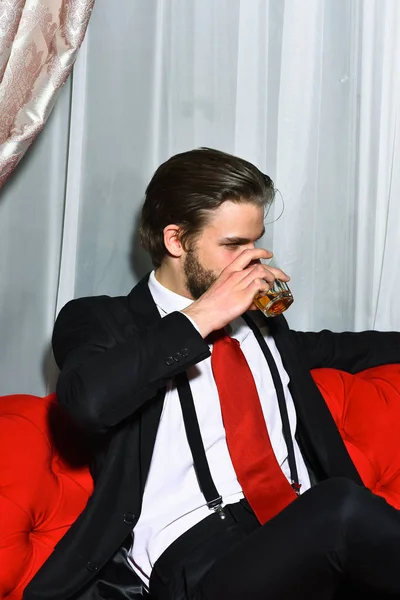 Bearded man, businessman holding glass of whiskey in red tie — Stock Photo, Image