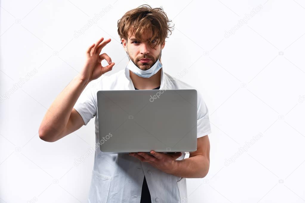Bearded caucasian doctor or postgraduate student with laptop in mask
