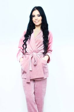 Gülümseyen mutlu kız pembe kadife pijamayla poz veriyor.