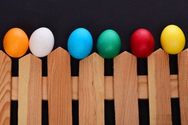 siyah arka plan üzerine ahşap çit boyalı Paskalya renkli yumurta
