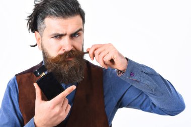 Sakallı adam ciddi bir parfüm tutuyor.