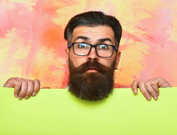 Szakállas férfi meglepett arc szemüvegben színes háttér — Stock Fotó
