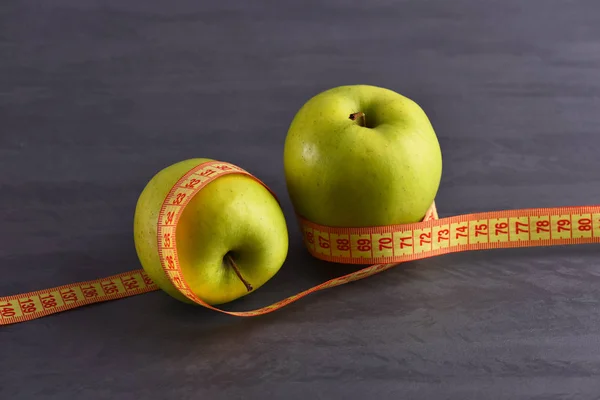 Jablka s měřicí páska nebo centimetr na šedé studio pozadí — Stock fotografie