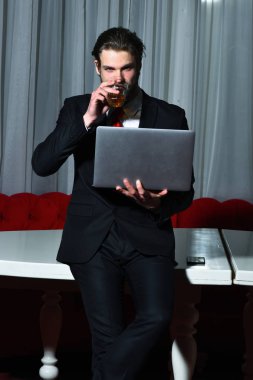 Sakallı adam, bir bardak viski, cep telefonu, dizüstü bilgisayarı olan iş adamı.