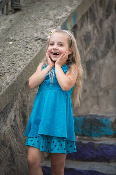 small baby girl with surprised face in blue dress outdoor