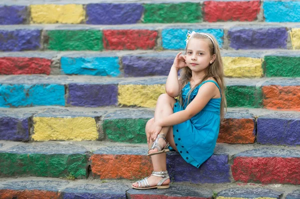 Маленька дівчинка в блакитній сукні на барвистих сходах — стокове фото