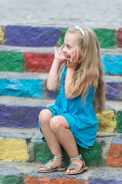 Kis boldog baba lány színes lépcsőn kék ruha — Stock Fotó