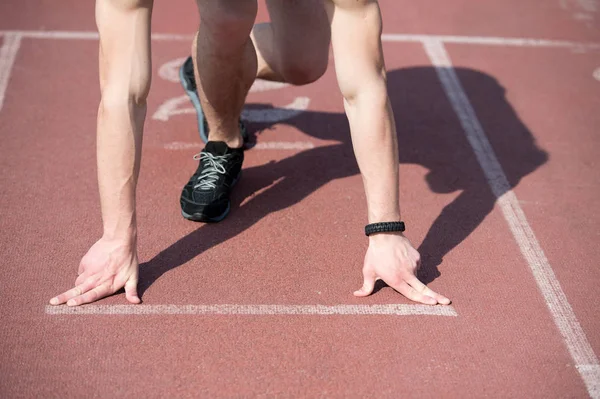 Hombre corredor con las manos musculosas, las piernas comienzan en pista de atletismo — Foto de Stock