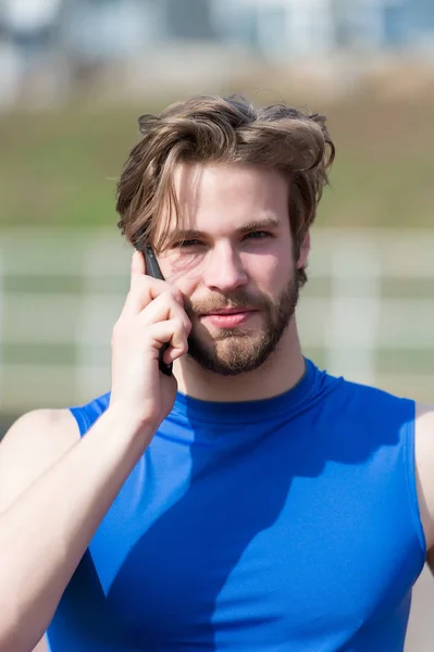Спортивний бородатий щасливий чоловік з м'язовим тілом тримає мобільний телефон — стокове фото