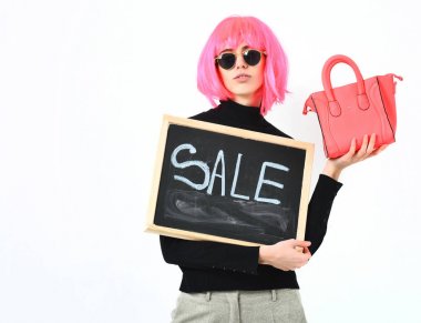 Kız peruklu çanta ve yiyecek ve satılık yazı taşıyor.