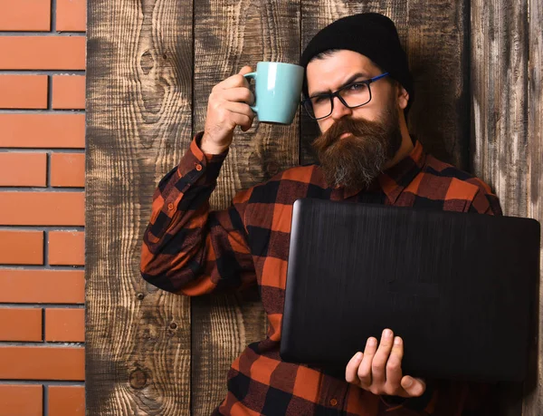 Barbudo brutal caucásico hipster celebración portátil con taza —  Fotos de Stock