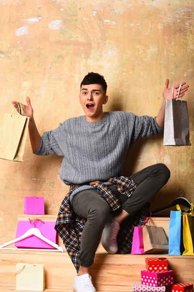 Askılar, alışveriş torbaları, kutuları ile şaşırmış mutlu genç adam — Stok fotoğraf