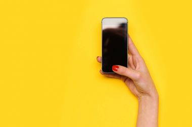 Kız dokunmatik cep telefonu ekran sarı arka plan üzerinde el ile