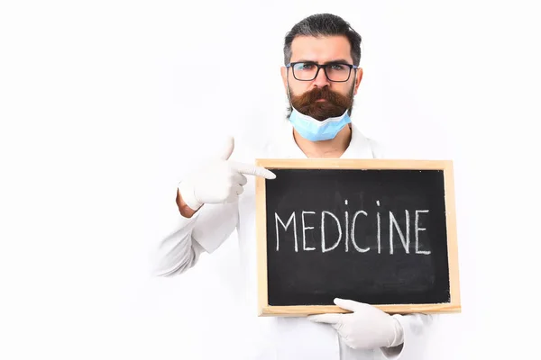 Médico caucasiano barbudo segurando seringa e papelão com inscrição em Medicina — Fotografia de Stock