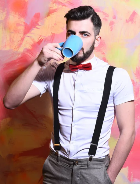 bearded man drinking tea or coffee with serious face