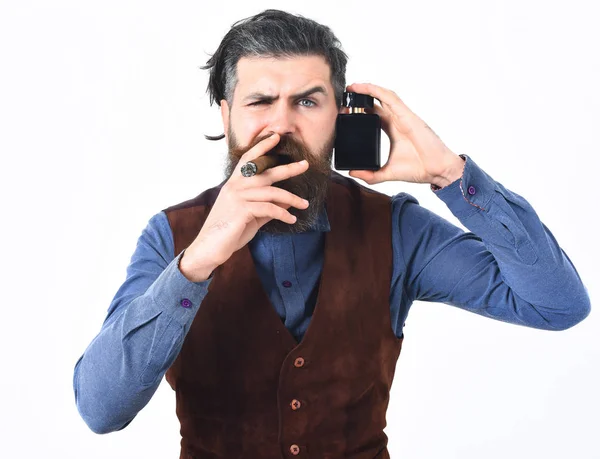 Homem barbudo fumar charuto com rosto sério, segurando perfume — Fotografia de Stock
