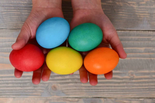 Manos femeninas de niña sosteniendo huevos de colores — Foto de Stock