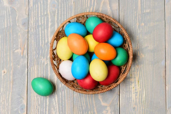 Huevos pintados de colores en la cesta sobre fondo de madera, fiesta de Pascua — Foto de Stock