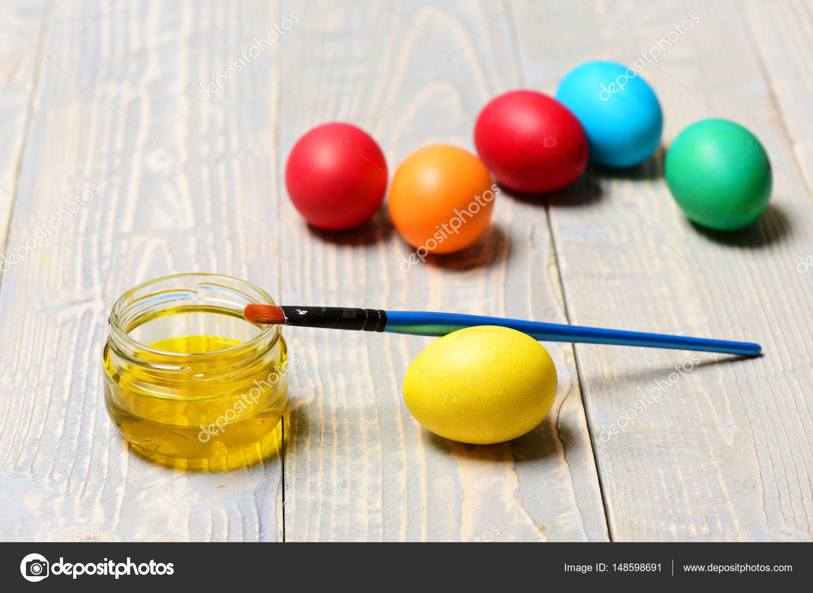 Arte e disegno giallo barattolo di vernice con il pennello o una spazzola su fondo di legno dipinta uova colorate a mano sul tavolo felice Pasqua