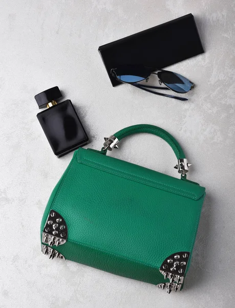 small womans leather green bag with sunglasses, perfume and case