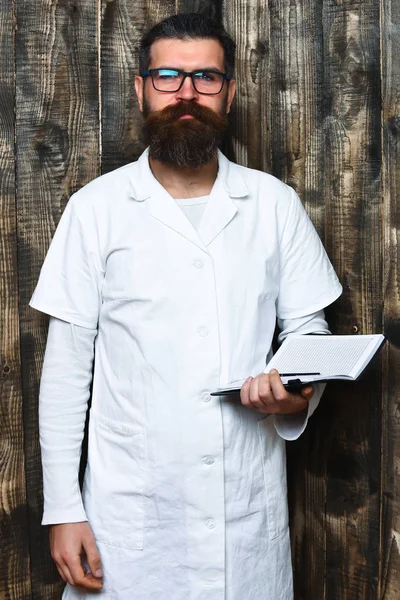 Bearded brutal caucasian doctor or postgraduate student with notebook