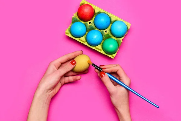 Mãos femininas com ovos de páscoa pintados coloridos com escova — Fotografia de Stock