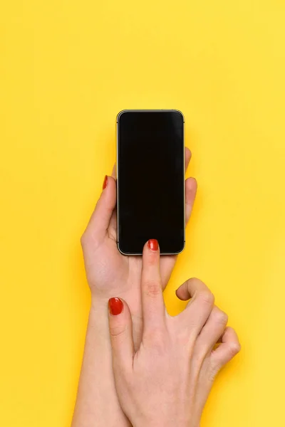 Girl touch mobile phone screen with hand on yellow background — Stock Photo, Image