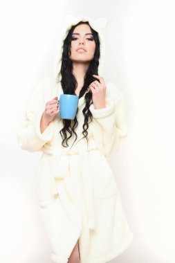 Fincanlı bej kadife bornozla poz veren seksi kız.