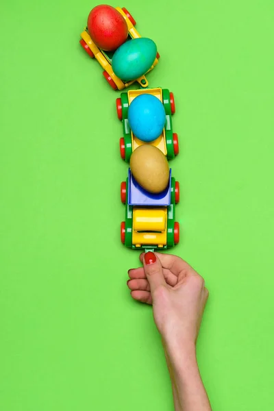 Mão feminina com ovos de páscoa coloridos em caminhão carro brinquedo — Fotografia de Stock