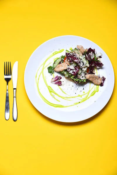 Peixe cozido com folhas de salada fresca no fundo amarelo — Fotografia de Stock